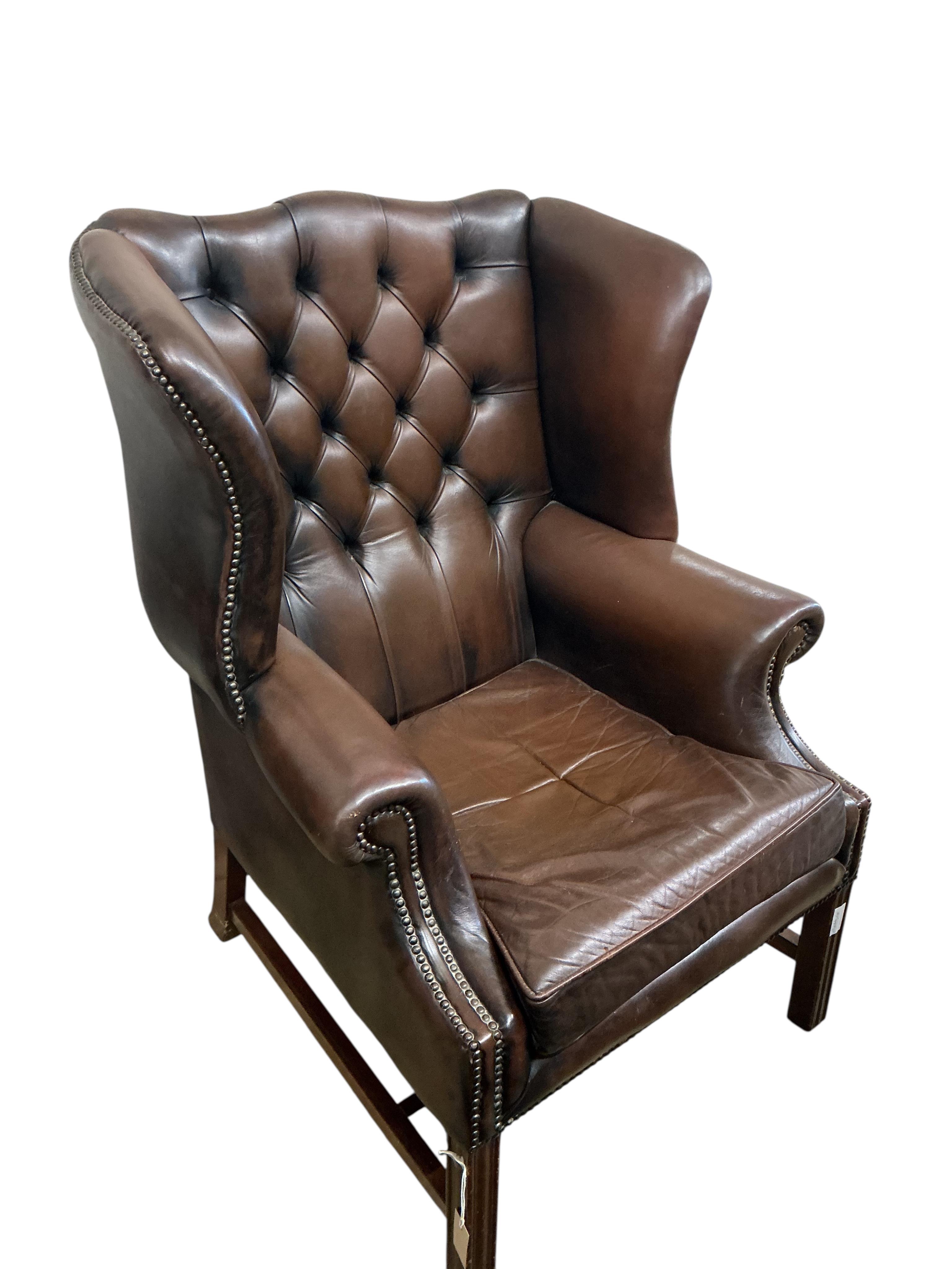 A reproduction George III style buttoned brown leather wing armchair, width 84cm, depth 70cm, height 110cm